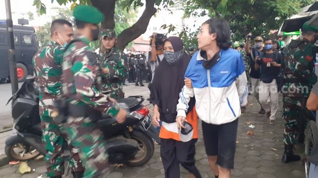 Seorang pelajar dijemput ibunya saat ikut demo dengan mahasiswa terkait kinerja setahun Jokowi-Ma’ruf di Istana Bogor, Selasa (20/10/2020). [Suara.com/Andi Ahmad Sulaendi]