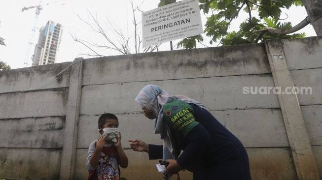 Satgas Padat Karya Penanganan COVID-19 Kelurahan Pejaten Barat memberikan sosialisasi protokol kesehatan kepada seorang anak di Kelurahan Pejaten Barat, Pasar Minggu, Jakarta, Kamis (22/10/2020). [Suara.com/Angga Budhiyanto]