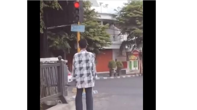 Pria pejalan kaki ini berhenti saat lampu merah (Facebook)