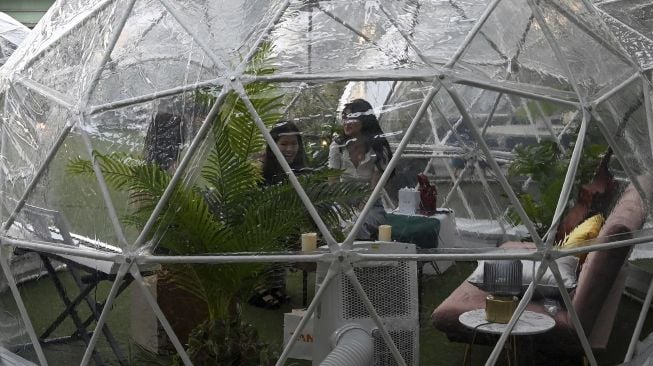 Pengunjung menyantap makanan di dalam instalasi tempat makan berbentuk kubah (dining dome) di Capitol Singapore Outdoor Plaza, Singapura pada (21/10/2020). [ROSLAN RAHMAN / AFP]