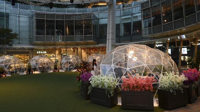 Pengunjung menyantap makanan di dalam instalasi tempat makan berbentuk kubah (dining dome) di Capitol Singapore Outdoor Plaza, Singapura pada (21/10/2020). [ROSLAN RAHMAN / AFP]