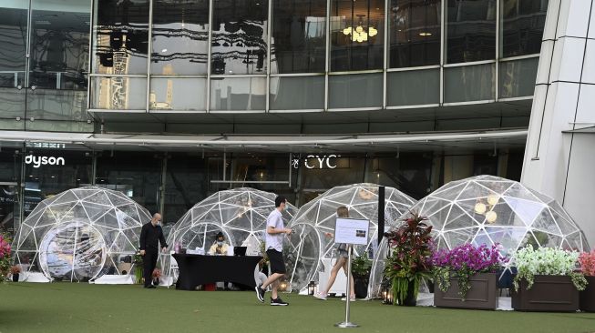 Pengunjung menyantap makanan di dalam instalasi tempat makan berbentuk kubah (dining dome) di Capitol Singapore Outdoor Plaza, Singapura pada (21/10/2020). [ROSLAN RAHMAN / AFP]