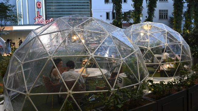 Pengunjung menyantap makanan di dalam instalasi tempat makan berbentuk kubah (dining dome) di Capitol Singapore Outdoor Plaza, Singapura pada (21/10/2020). [ROSLAN RAHMAN / AFP]