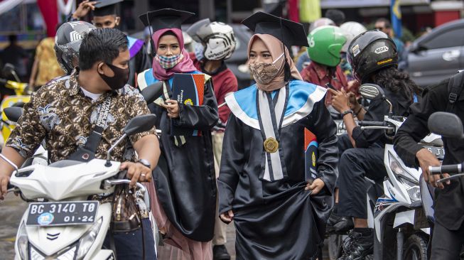 Sejumlah wisudawan bersama pendamping antre untuk mengikuti prosesi wisuda secara "Drive Thru" di Kampus Politeknik Negeri Sriwijaya (Polsri) Palembang, Sumatera Selatan, Sabtu (24/10/2020). [ANTARA FOTO/Nova Wahyudi]