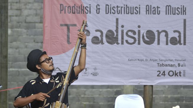 Perajin Rizal Abdulhadi memainkan alat musik tradisional berbahan bambu buatannya saat kegiatan Lokakarya Produksi dan Distribusi Alat Musik Tradisional di kawasan Desa Sangketan, Tabanan, Bali, Sabtu (24/10/2020). [ANTARA FOTO/Fikri Yusuf]