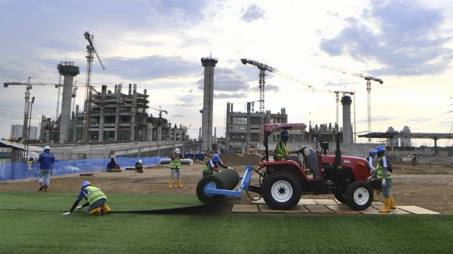 Pekerja menyelesaikan pemasangan rumput untuk lapangan latih di Kompleks Stadion Utama Jakarta International Stadium (JIS), Jakarta, Jumat (23/10/2020). [ANTARA FOTO/Puspa Perwitasari]