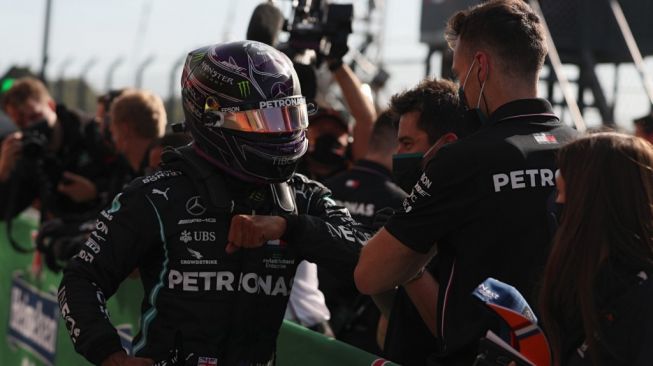 Pebalap Mercedes, Lewis Hamilton melakukan selebrasi di parc ferme usai meraih pole position pada sesi kualifikasi F1 GP Portugal 2020 di Sirkuit Internasional Algarve, Sabtu (24/10/2020) malam WIB. [JOSE SENA GOULAO / POOL / AFP]