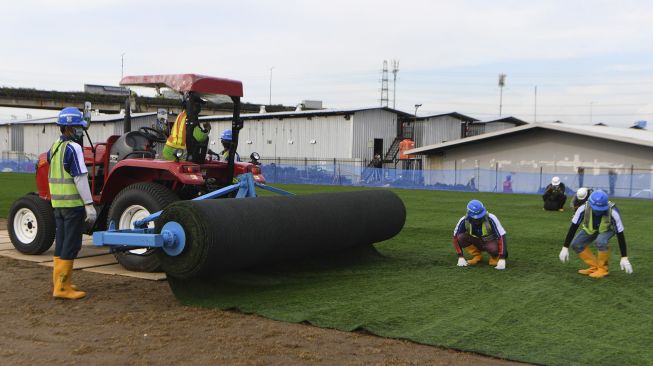 Pekerja menyelesaikan pemasangan rumput untuk lapangan latih di Kompleks Stadion Utama Jakarta International Stadium (JIS), Jakarta, Jumat (23/10/2020). [ANTARA FOTO/Puspa Perwitasari]