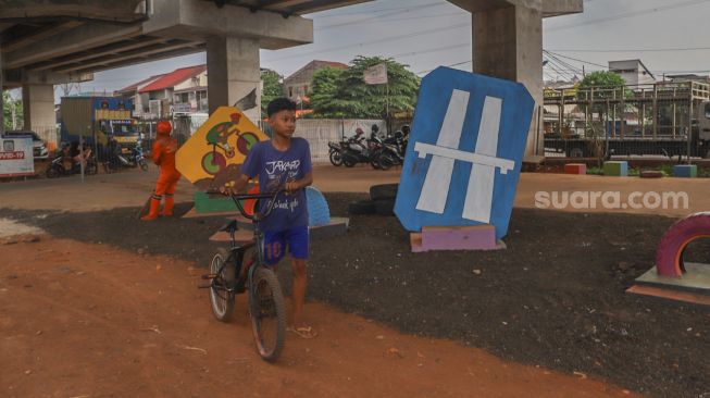 Seorang anak saat datang untuk mencoba jalur trek sepeda di Bike Park Pilar Jati, Kolong Tol Becakayu, Jakarta Timur, Minggu (25/10). [Suara.com/Alfian Winanto]