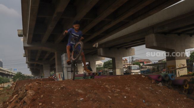 Seorang anak menjajal area lintasan Pump Track di Bike Park Pilar Jati, Kolong Tol Becakayu, Jakarta Timur, Minggu (25/10). [Suara.com/Alfian Winanto]