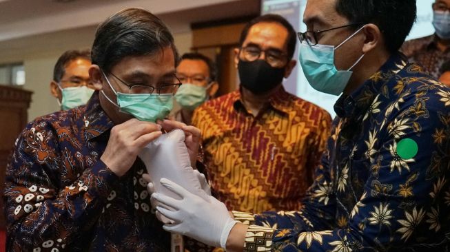 Dirut RSUP Dr Sardjito, Rukmono (kiri) menampung nafas untuk diuji dengan alat tes cepat COVID-19 melalui hembusan nafas yang diberi nama GeNose hasil inovasi Universitas Gadjah Mada (UGM) Yogyakarta saat peluncuran dimulainya penelitian GeNose di RSUP Dr. Sardjito, Sleman, D.I Yogyakarta, Senin (26/10/2020). [ANTARA FOTO/Andreas Fitri Atmoko]
