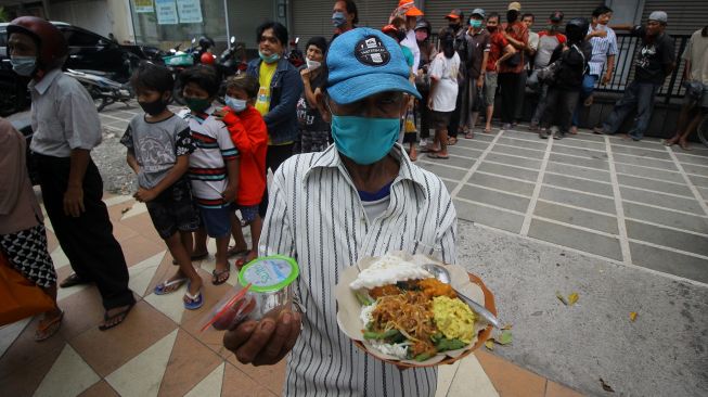 Warga memperlihatkan menu makan gratis yang didapatkan dari gerobak makanan milik Setiyono di jalan Kedungsari, Surabaya, Jawa Timur, Selasa (27/10/2020).  [ANTARA FOTO/Moch Asim]

