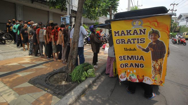 Warga mengantre untuk mendapatkan makanan secara gratis di gerobak makanan milik Setiyono di jalan Kedungsari, Surabaya, Jawa Timur, Selasa (27/10/2020).  [ANTARA FOTO/Moch Asim]
