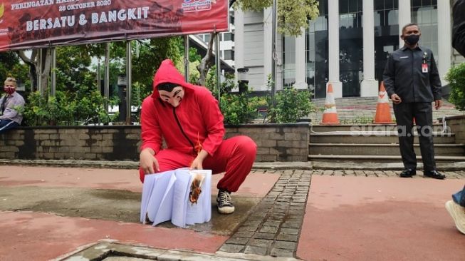 Pria Bertopeng Bakar, Sobek dan Buang Naskah UU Ciptaker di Depan Gedung MK