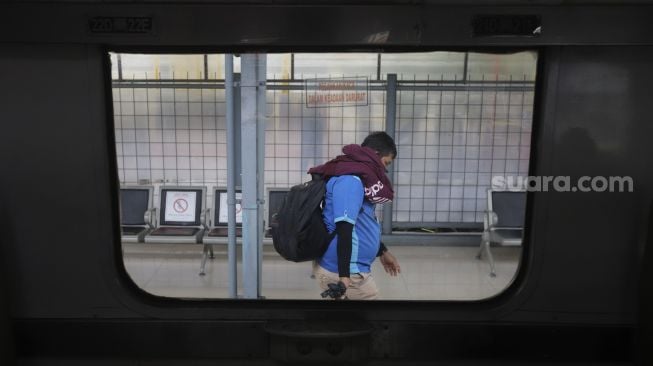 Seorang calon penumpang berjalan menuju rangkaian Kereta Api Matarmaja yang berhenti di Stasiun Pasar Senen, Jakarta, Selasa (27/10/2020). [Suara.com/Angga Budhiyanto]