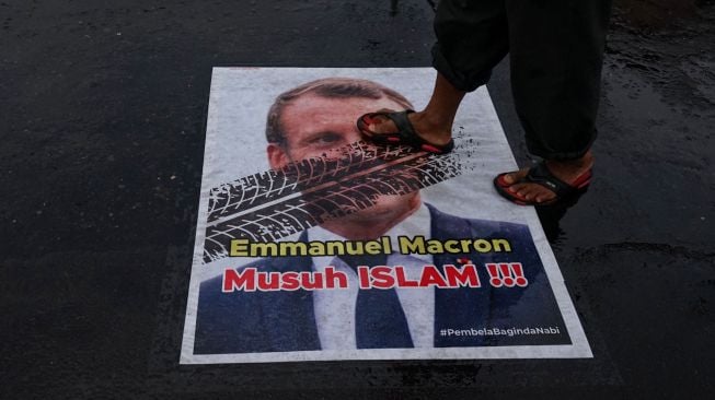 Warga menginjak poster berwajah presiden Prancis Emmanuel Macron yang ditempel di simpang Jalan Kauman, Yogyakarta, Rabu (28/10/2020).  [ANTARA FOTO/Andreas Fitri Atmoko]