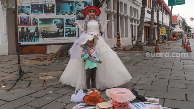 Anak - anak berswafoto dengan cosplayer di Kawasan Kota Tua, Jakarta Barat, Kamis (29/10). [Suara.com/Alfian Winanto]