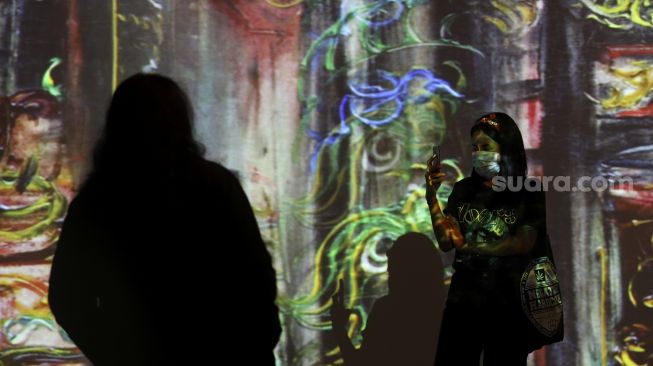 Pengunjung mengabadikan karya proyeksi video mapping di pameran imersif Affandi: Alam, Ruang, Manusia di Galeri Nasional Indonesia, Jakarta, Jumat (30/10/2020). [Suara.com/Angga Budhiyanto]