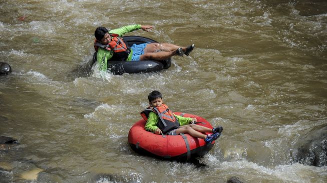 Sejumlah warga bersama Komunitas Sungai Cikapundung menyusuri Sungai Cikapundung menggunakan ban karet di Tamansari, Bandung, Jawa Barat, Sabtu (31/10/2020). [ANTARA FOTO/Raisan Al Farisi]