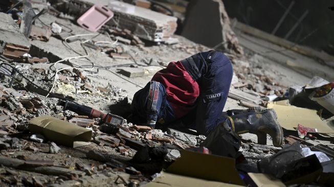 Tim penyelamat mencari korban selamat di antara puing-puing bangunan yang runtuh setelah gempa bumi yang dahsyat melanda pantai barat Turki dan sebagian Yunani, di Izmir, Sabtu (31/10/2020). [OZAN KOSE / AFP]