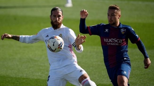 Pemain Real Madrid Sergio Ramos berebut bola dengan pemain SD Huesca dalam pertandingan La Liga yang berlangsung di Estadio Alfredo Di Stefano, Sabtu (31/10/2020). [AFP]