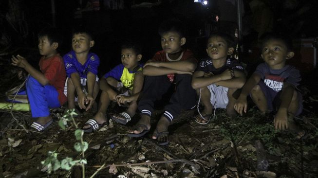 Sejumlah anak menyaksikan pemutaran film layar tancap di kawasan Serua, Bojongsari, Depok, Jawa Barat, Sabtu (19/9/2020). [Suara.com/Angga Budhiyanto]