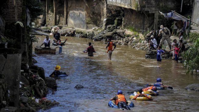 Sejumlah warga bersama Komunitas Sungai Cikapundung menyusuri Sungai Cikapundung menggunakan ban karet di Tamansari, Bandung, Jawa Barat, Sabtu (31/10/2020). [ANTARA FOTO/Raisan Al Farisi]