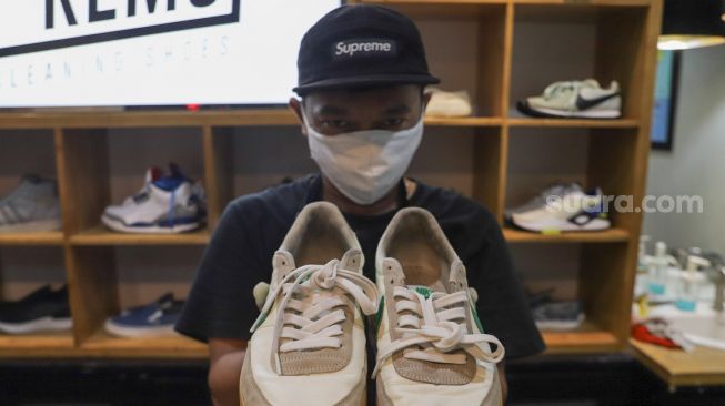 Kru menunjukkan sepatu pelanggan yang sudah dibersihkan di Cleaning Shoes Kicks Kemon, Haji Nawi, Jakarta Selatan, Minggu (1/11). [Suara.com/Alfian Winanto]