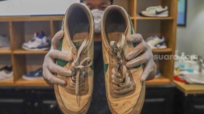 Kru menunjukkan sepatu kotor yang akan dicuci di Cleaning Shoes Kicks Kemon, Haji Nawi, Jakarta Selatan, Minggu (1/11). [Suara.com/Alfian Winanto]