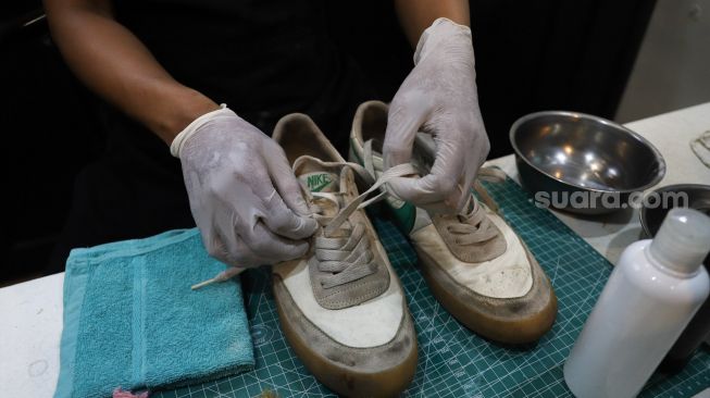 Kru melepas tali sepatu untuk dibersihkan di Cleaning Shoes Kicks Kemon, Haji Nawi, Jakarta Selatan, Minggu (1/11). [Suara.com/Alfian Winanto]