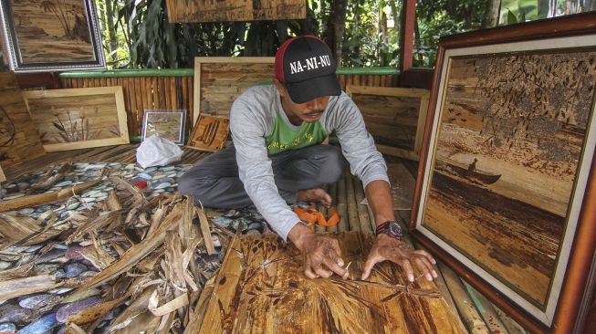 Perajin menyelesaikan lukisan dari pelepah pisang kering di Galeri Kalakay, Tapos, Depok, Jawa Barat, Minggu (1/11/2020). [ANTARA FOTO/Asprilla Dwi Adha]