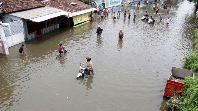 Pengendara sepeda motor mendorong kendaraannya saat menerobos jalan yang tergenang banjir di kawasan jalan raya Gempol, Pasuruan, Jawa Timur, Senin (2/11/2020). [ANTARA FOTO/Umarul Faruq]