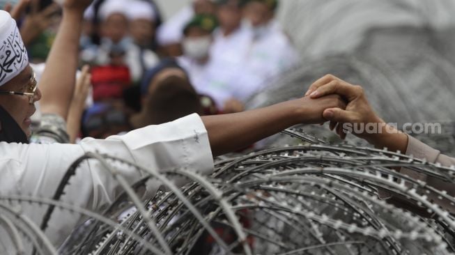 Massa yang tergabung dalam Aliansi Umat Islam bersalaman dengan aparat kepolisian saat melakukan aksi unjuk rasa di sekitar Kedubes Prancis, Jakarta, Senin (2/11/2020). [Suara.com/Angga Budhiyanto]