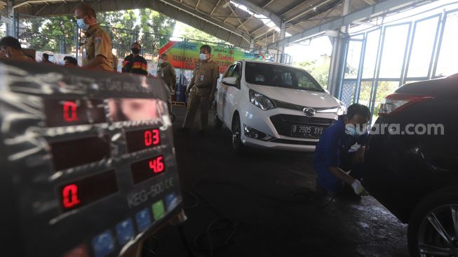 Petugas melakukan uji emisi kendaraan bermotor di Kantor Dinas Lingkungan Hidup DKI Jakarta, Kramat Jati, Jakarta, Selasa (3/11/2020). [Suara.com/Angga Budhiyanto]