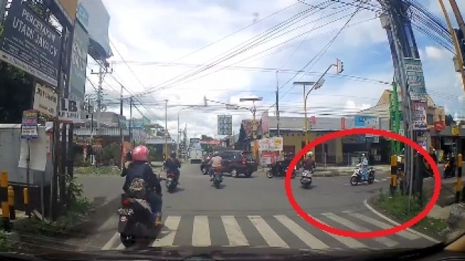 Emak-emak naik motor tanpa menggunakan helm nekat terobos lampu merah (Facebook)