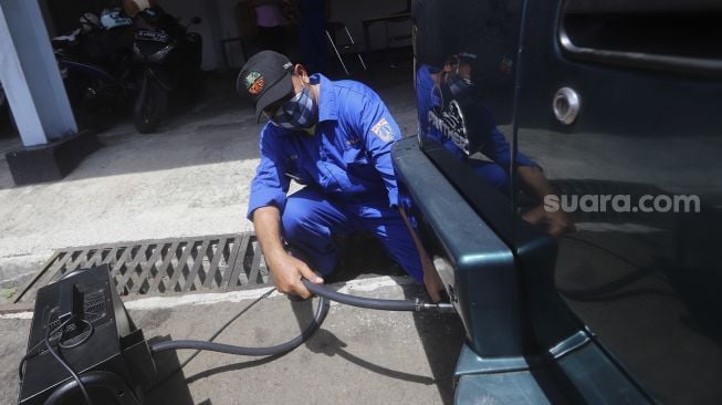 Petugas melakukan uji emisi kendaraan bermotor di Kantor Dinas Lingkungan Hidup DKI Jakarta, Kramat Jati, Jakarta, Selasa (3/11/2020). [Suara.com/Angga Budhiyanto]