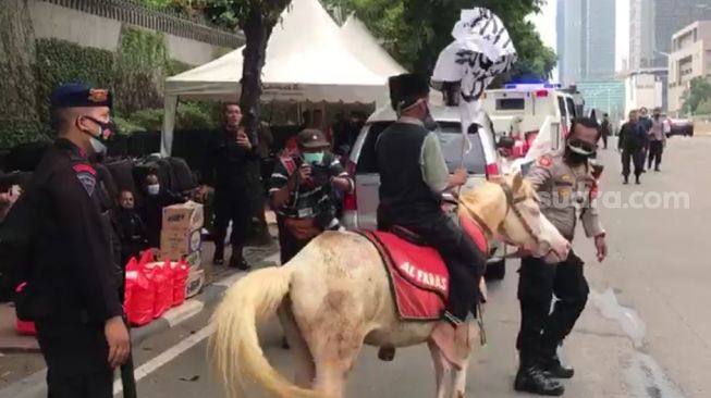 Seorang bocah menunggangi kuda saat mengikuti aksi unjuk rasa di depan Kedubes Prancis, Jakarta Pusat, Rabu (4/11/2020). [Suara.com/Bagaskara Isdiansyah]