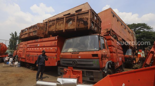 Petugas keamanan berjaga di antara tumpukan bangkai kendaraan dinas yang sudah tidak layak pakai di Kantor Dinas Lingkungan Hidup DKI Jakarta, Kramat Jati, Jakarta, Rabu (4/11/2020). [Suara.com/Angga Budhiyanto]