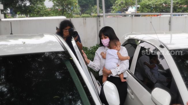 Aktris Vanessa Angel akan masuk ke mobilnya sambil menggendong anaknya, Gala Sky usai  menjalani sidang putusan terkait kasus narkoba di Pengadilan Negeri Jakarta Barat, Kamis (5/11). [Suara.com/Alfian Winanto]