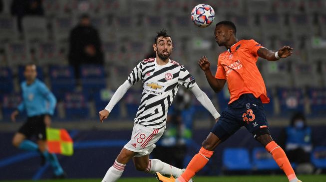 Gelandang Manchester United Bruno Fernandes (kiri) memperebutkan bola dengan bek Istanbul Basaksehir Boli Bolingoli selama pertandingan sepak bola Liga Champions UEFA grup H, antara Istanbul Basaksehir FK melawan Manchester United, di Stadion Basaksehir Fatih Terim, Kamis (5/11/2020) dini hari WIB. [OZAN ​​KOSE / AFP]