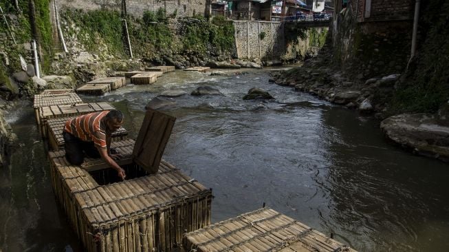 Warga membersihkan sampah yang menyangkut di keramba budidaya ikan di aliran Sungai Cikapundung, Bandung, Jawa Barat, Jumat (6/11/2020). [ANTARA FOTO/Novrian Arbi]