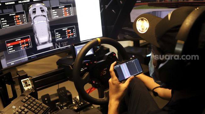 Seorang pembalap mengatur suspensi mobil balapnya saat melakukan sesi latihan menggunakan simulator balap di P1 Academy Motorsport Indonesia (ADMI), Kebayoran Baru, Jakarta, Jumat (6/11/2020). [Suara.com/Angga Budhiyanto]