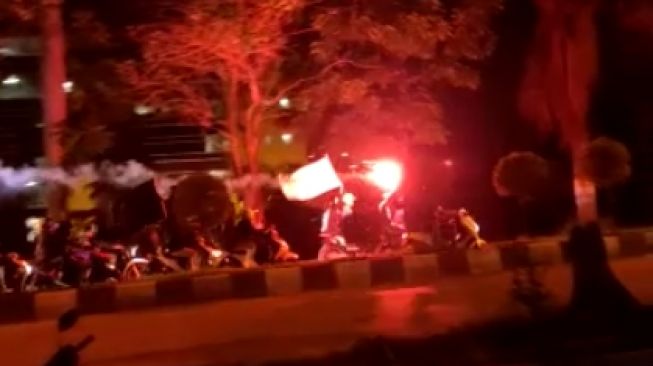 Konvoi kelompok bermotor dengan membawa bendera dan menyalakan flare di Jalan Dago, bandung, Sabtu (8/11/2020) malam. [Istimewa]