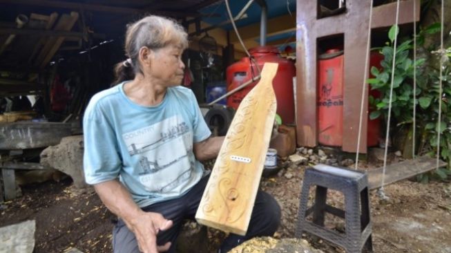 Christian Mara, seniman alat musik tradisional khas Dayak menunjukkan Sappe karyanya. (Suara.com/Eko Susanto)