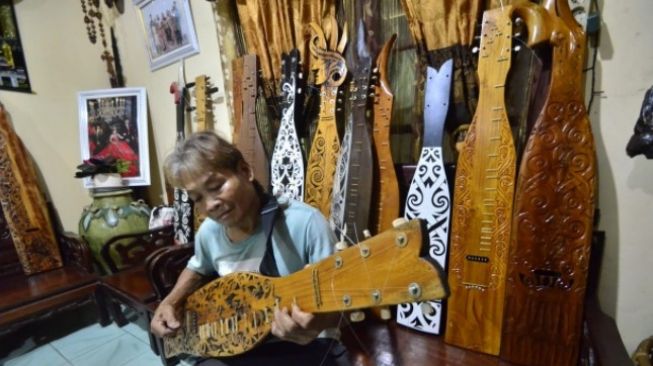 Christian Mara, seniman alat musik tradisional khas Dayak memainkan Sappe. (Suara.com/Eko Susanto)