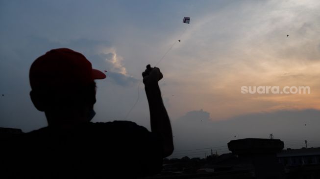 Seorang warga menerbangkan layangannya di samping Fly Over Kalibata, Jakarta Selatan, Senin (9/11). [Suara.com/Alfian Winanto]