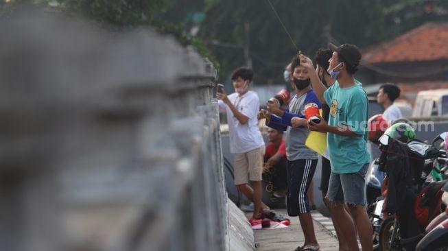 Warga menerbangkan layangannya di samping Fly Over Kalibata, Jakarta Selatan, Senin (9/11). [Suara.com/Alfian Winanto]