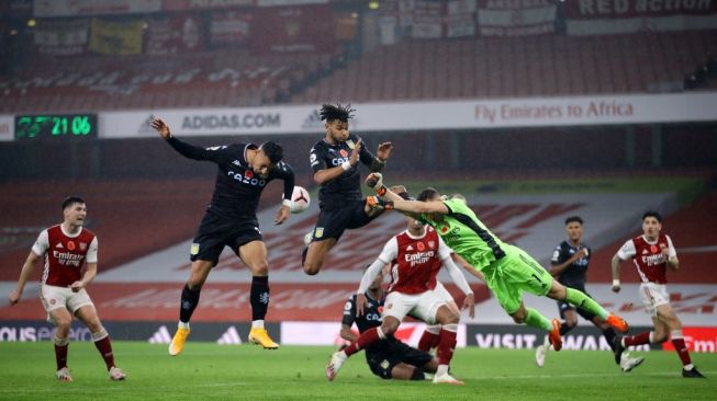 Penjaga gawang Arsenal, Bernd Leno (kanan) mencoba meninju bola saat bek Aston Villa Inggris Tyrone Mings (tengah) dan striker Anwar El Ghazi (kedua dari kiri) berlari untuk menyundul bola selama pertandingan pekan kedelapan Liga Inggris di Emirates Stadium, London Senin (9/11/2020). [Richard Heathcote / POOL / AFP]