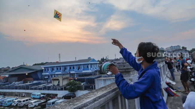 Seorang warga menerbangkan layangannya di samping Fly Over Kalibata, Jakarta Selatan, Senin (9/11). [Suara.com/Alfian Winanto]