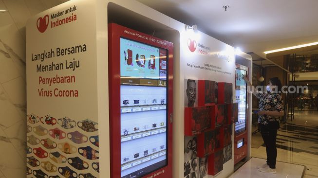 Pengunjung memilih masker yang dijual pada "vending machine" di Senayan City Mall, Jakarta, Rabu (11/11/2020). [Suara.com/Angga Budhiyanto]